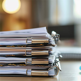 Pila de carpetas con documentos sujetos con pinzas metálicas